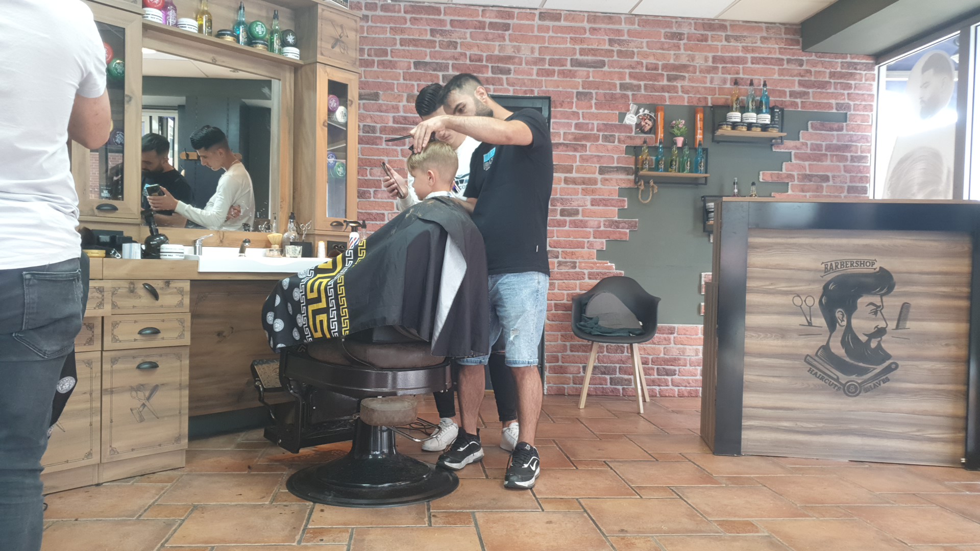 Drukte in de zaak, een jonge klant wordt geknipt