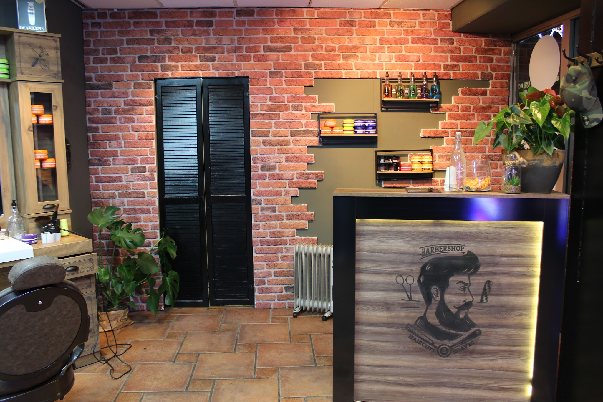Bakstenen wand en verlichte balie met het logo van Barbershop City