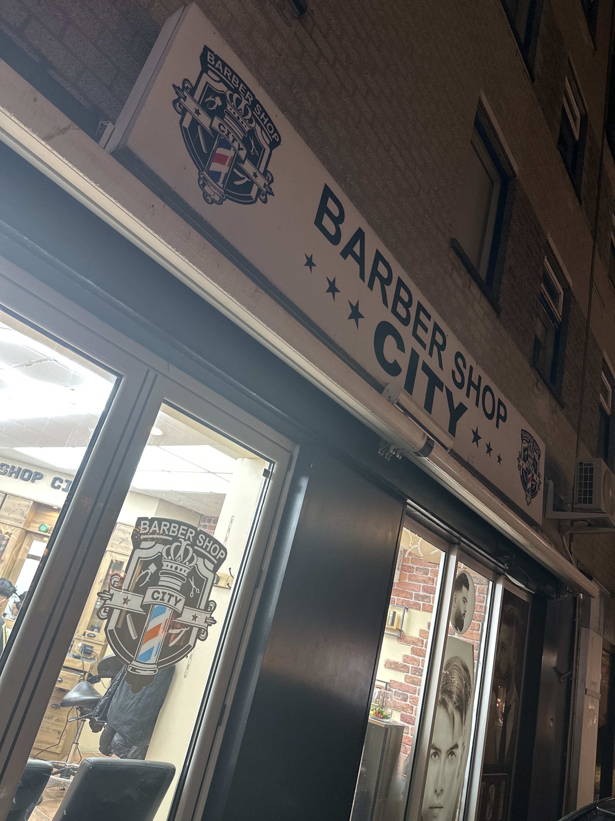 Gevel van Barbershop City met uithangbord en logo