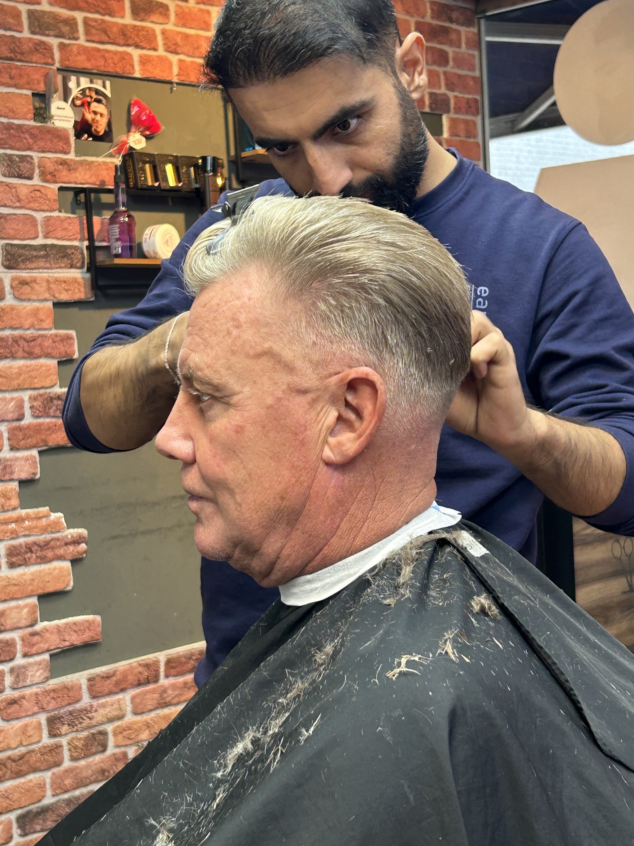 Barbier werkt een strakke grijze coupe af bij een klant